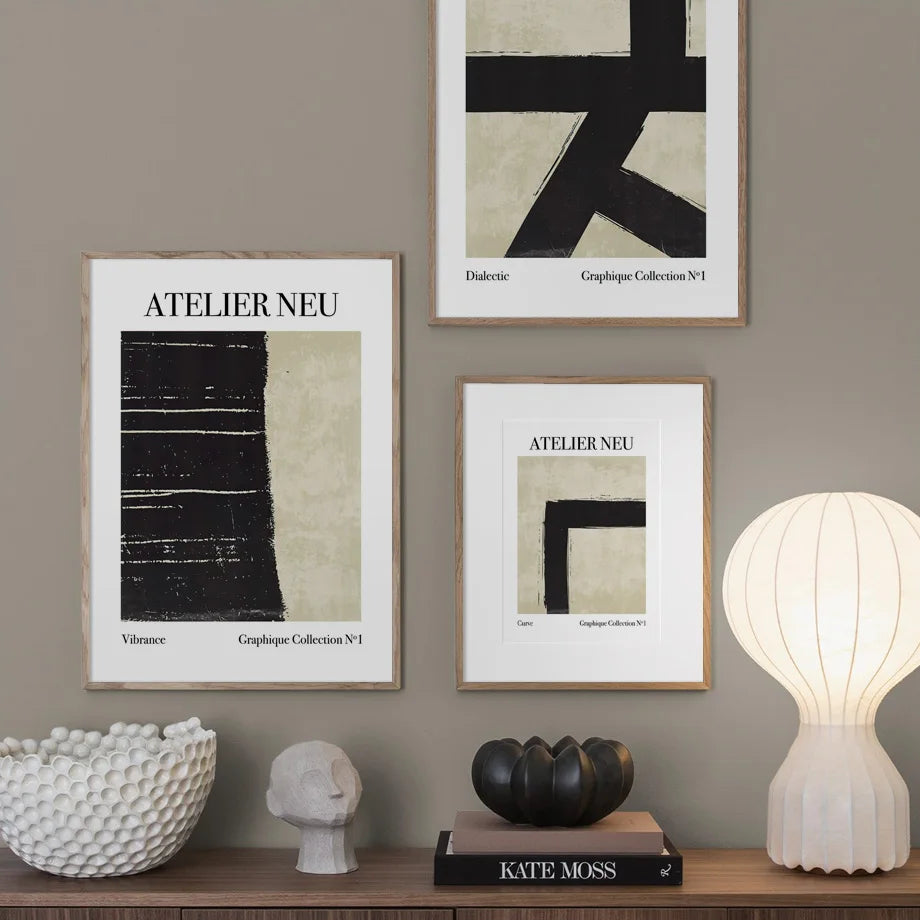 Three framed artworks on a wall with decorative items on a shelf below.