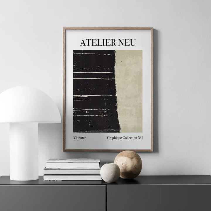 Framed artwork with 'ATELIER NEU' text on a wall above a shelf with decor items.