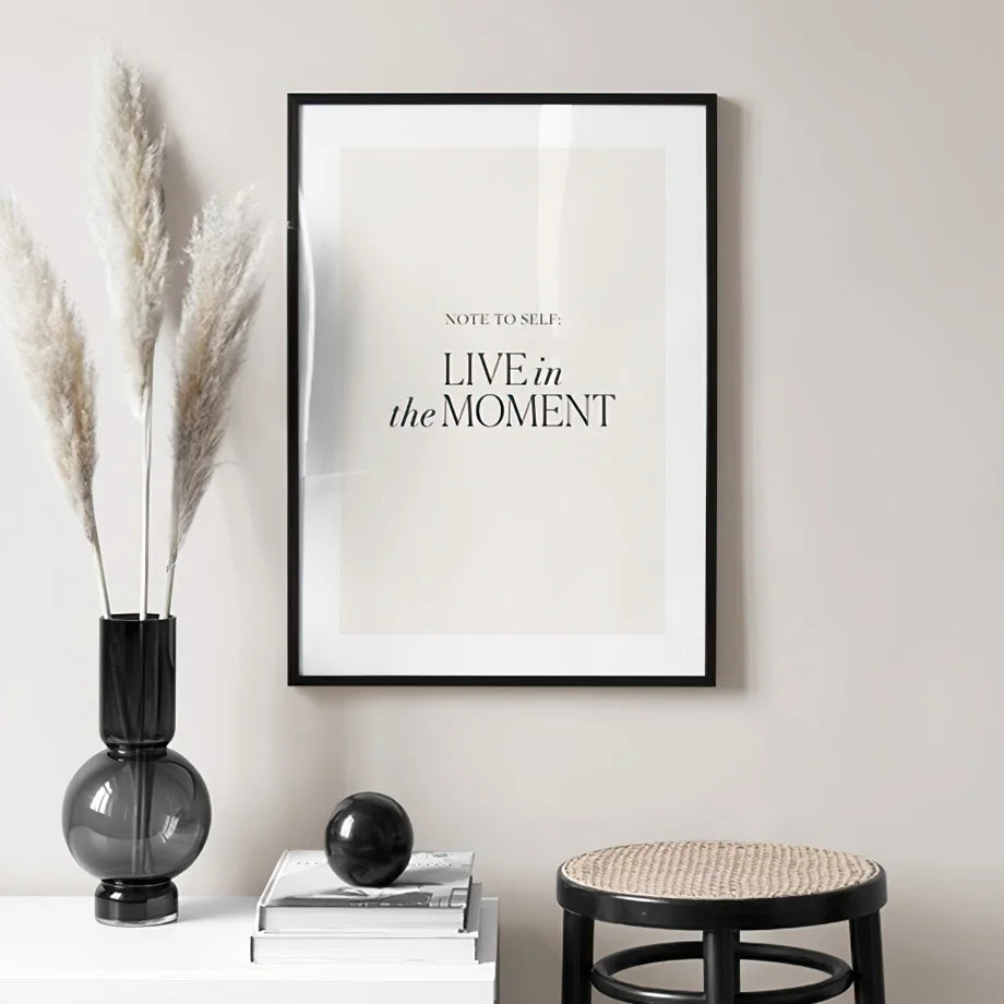 Live in the moment quote canvas poster on beige living room wall.