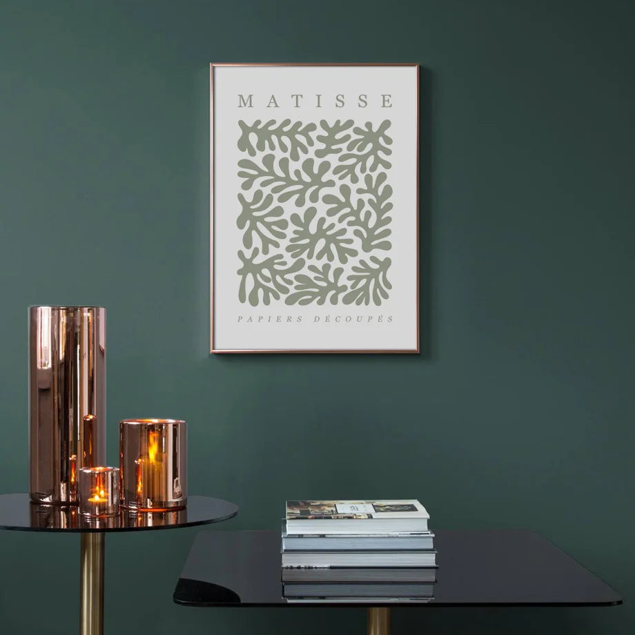 Framed Matisse print on a green wall with decorative items on tables.
