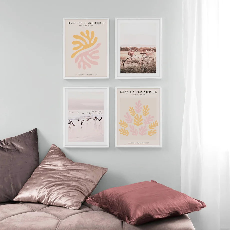 Four framed prints on a wall above a sofa with pillows.