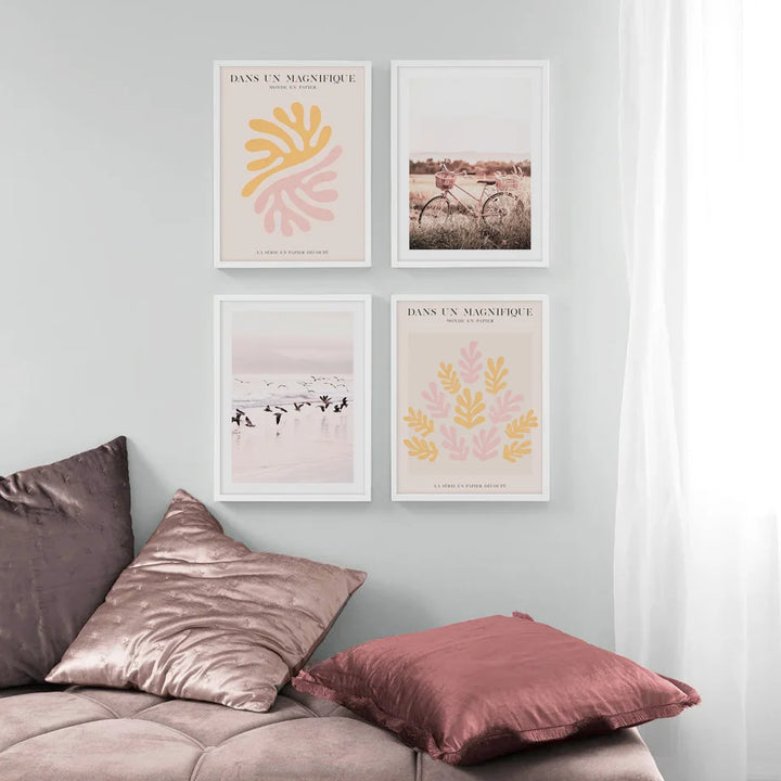 Four framed prints on a wall above a sofa with pillows.