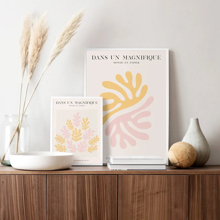 Two framed abstract art prints on a wooden shelf with decorative items.