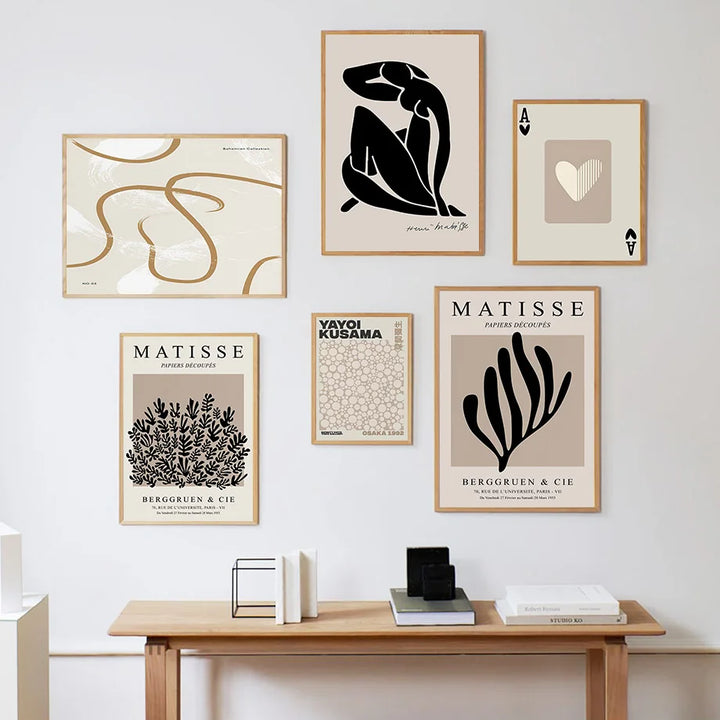 Neutral gallery wall of framed black and beige canvas prints above a wooden desk