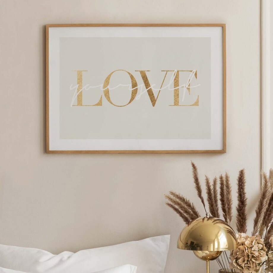 Gold love canvas poster on beige wall.